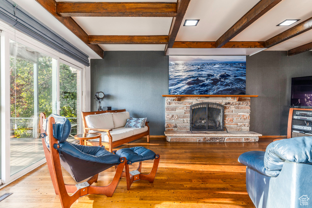 Living room featuring beam ceiling, a fireplace, and light wood-type flooring