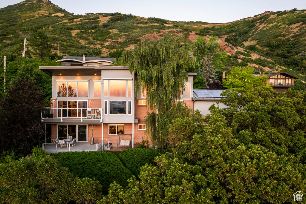 Rear view of house featuring a mountain view, a balcony, and solar panels