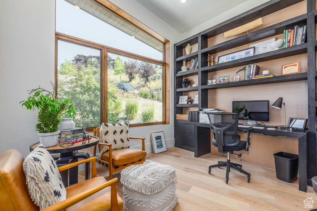 Office area featuring built in shelves and light hardwood / wood-style flooring