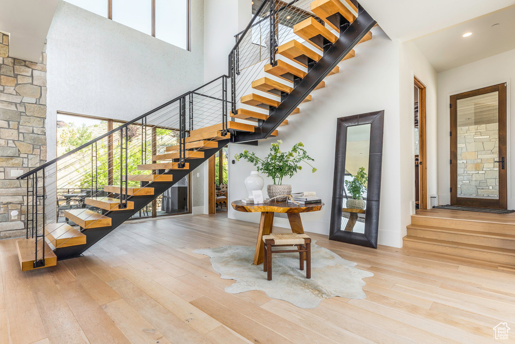 Stairway featuring a towering ceiling and light wood-type flooring