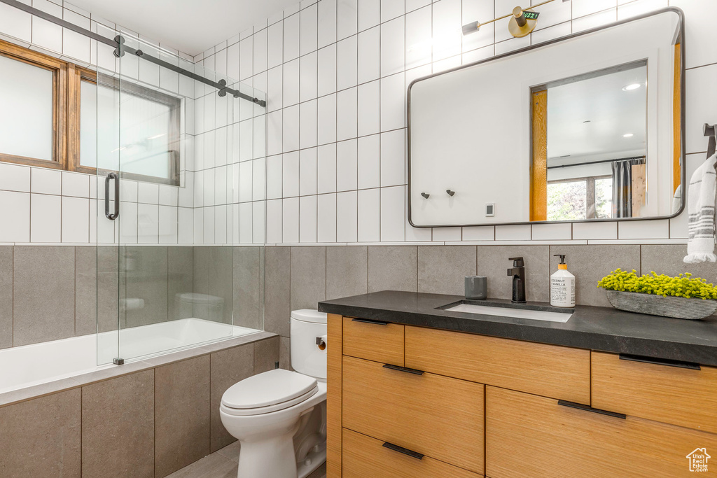 Bathroom with vanity, tasteful backsplash, toilet, and tile walls