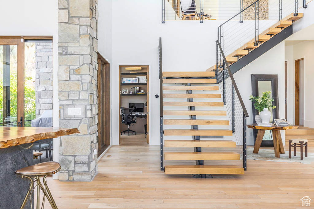 Stairs featuring light wood-type flooring and a towering ceiling