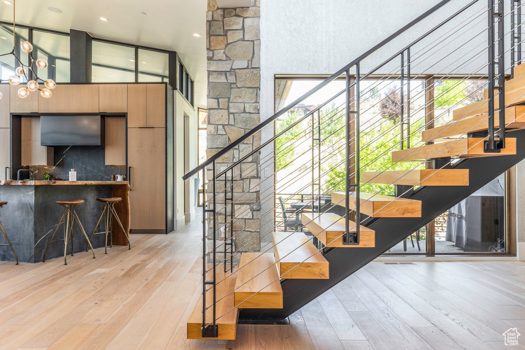 Stairs featuring wood-type flooring, high vaulted ceiling, and a chandelier