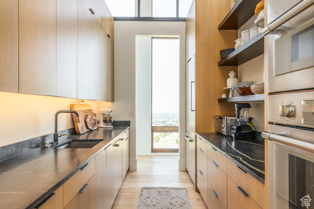 Kitchen with oven, sink, light wood-type flooring, and light brown cabinetry