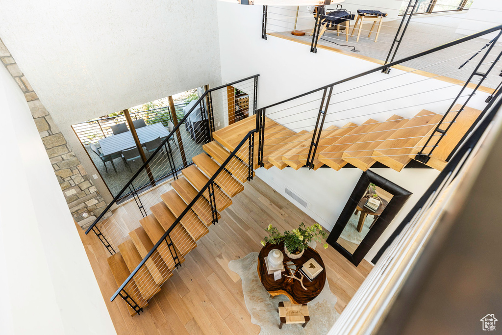 Stairs with a towering ceiling and light hardwood / wood-style flooring