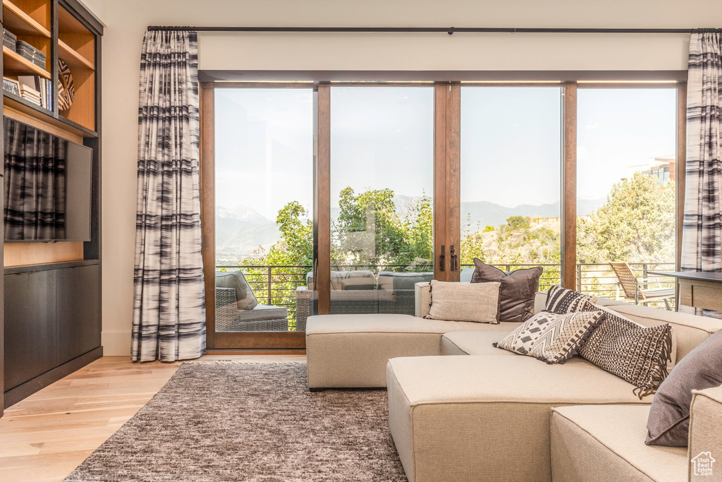 Living room with light hardwood / wood-style flooring, a mountain view, and a healthy amount of sunlight