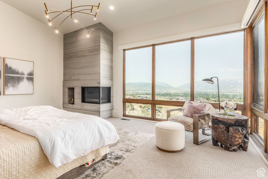 Carpeted bedroom with a large fireplace, a mountain view, and a chandelier