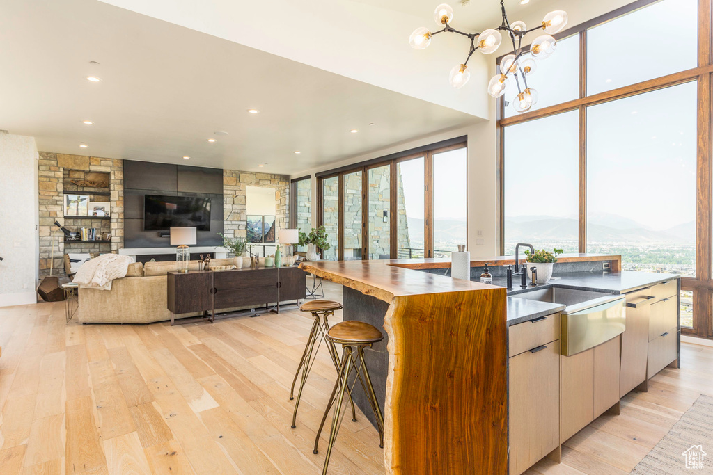 Kitchen featuring a notable chandelier, pendant lighting, light wood-type flooring, sink, and a kitchen island with sink