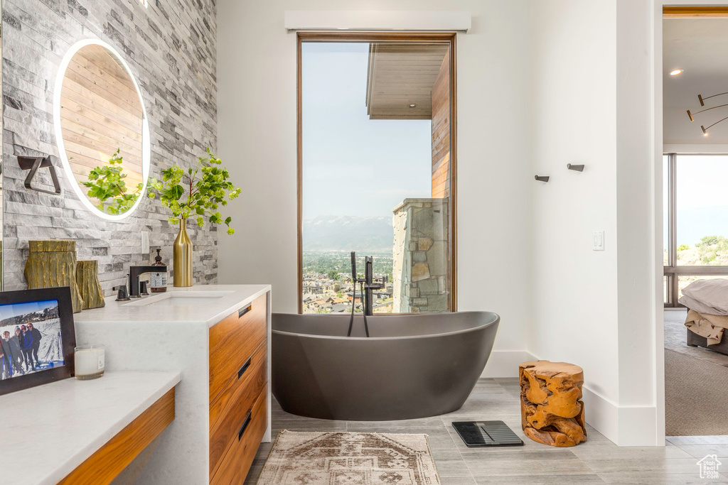 Bathroom with tile patterned floors, vanity, a tub to relax in, and a wealth of natural light