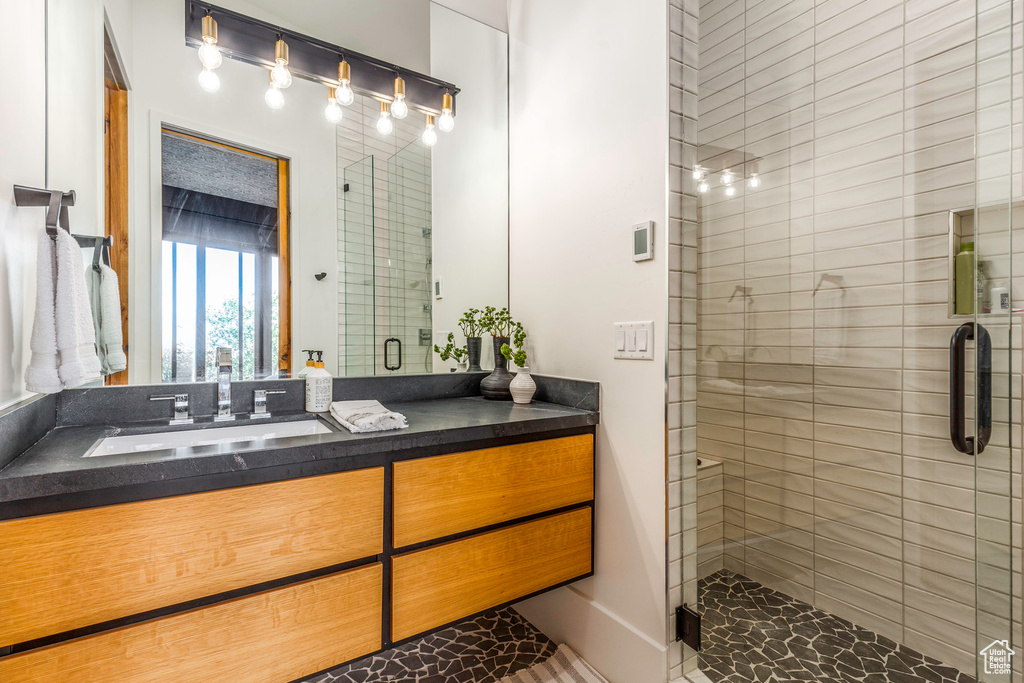 Bathroom featuring a shower with shower door and vanity