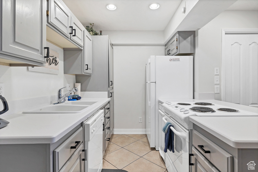 Kitchen with sink, white appliances, light tile patterned floors, and gray cabinetry