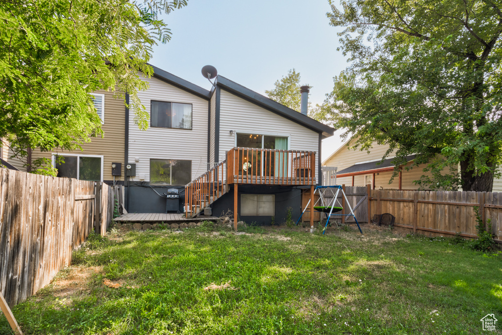 Rear view of property featuring a wooden deck and a lawn