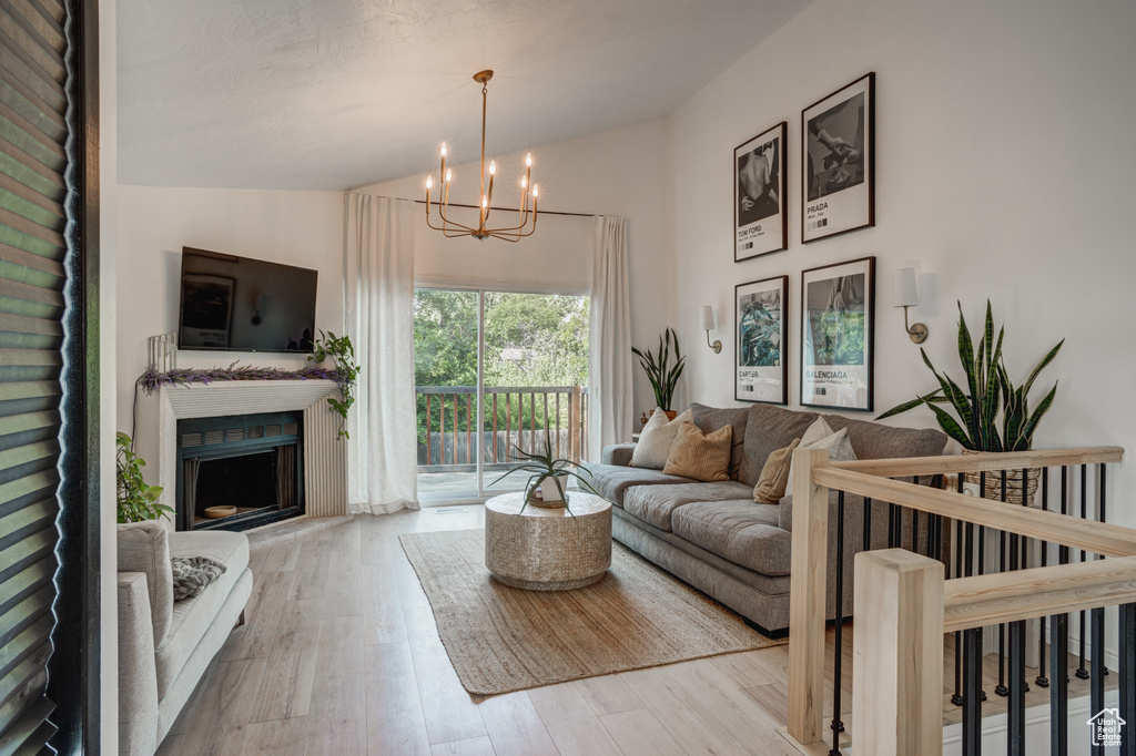 Living room featuring light wood-type flooring, vaulted ceiling, and a chandelier