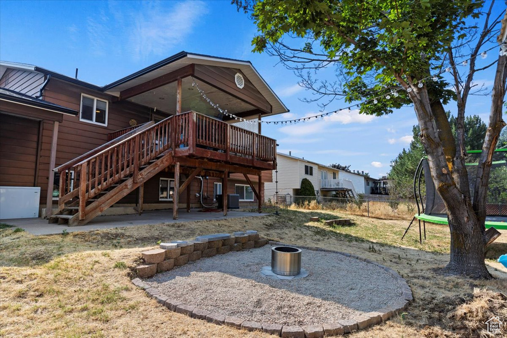 Rear view of house featuring a trampoline, central AC, a patio, and a deck