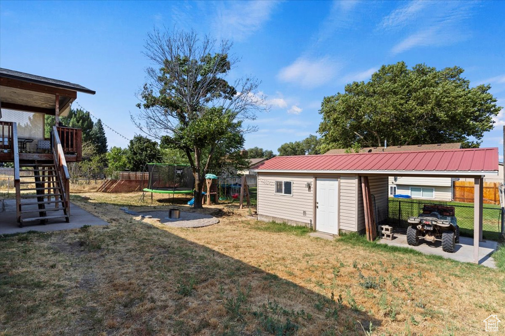 View of yard featuring a trampoline, a storage unit, and an outdoor fire pit