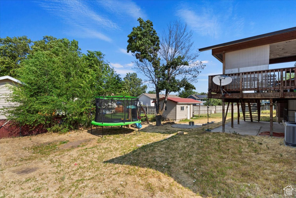 View of yard with a deck, a patio area, a shed, and a trampoline