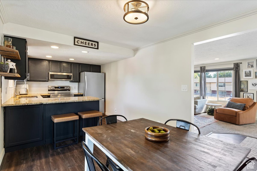 Dining space featuring dark wood-type flooring, crown molding, and sink