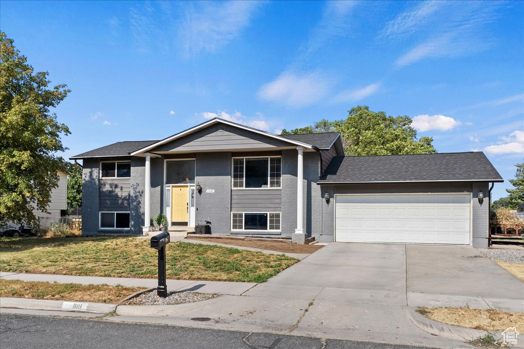 Bi-level home featuring a garage and a front lawn