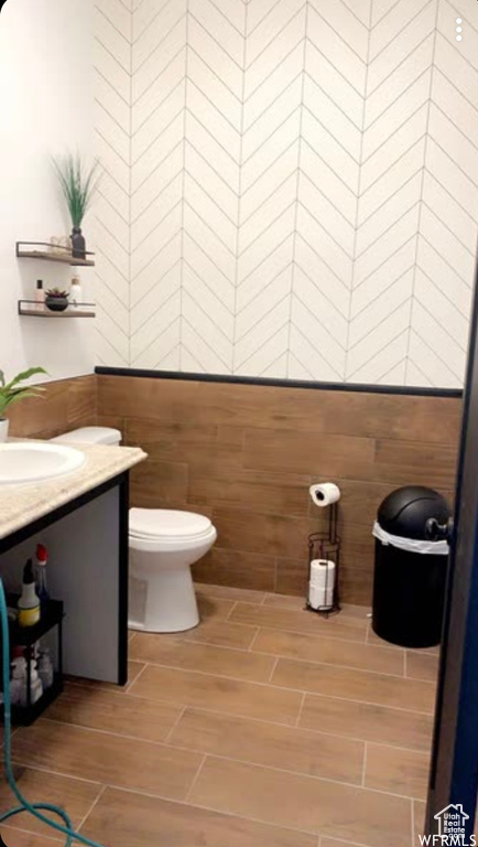 Bathroom featuring tile walls, toilet, and vanity