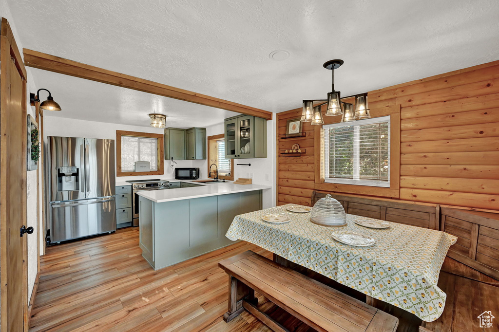 Dining area with sink, light hardwood / wood-style flooring, a textured ceiling, and log walls