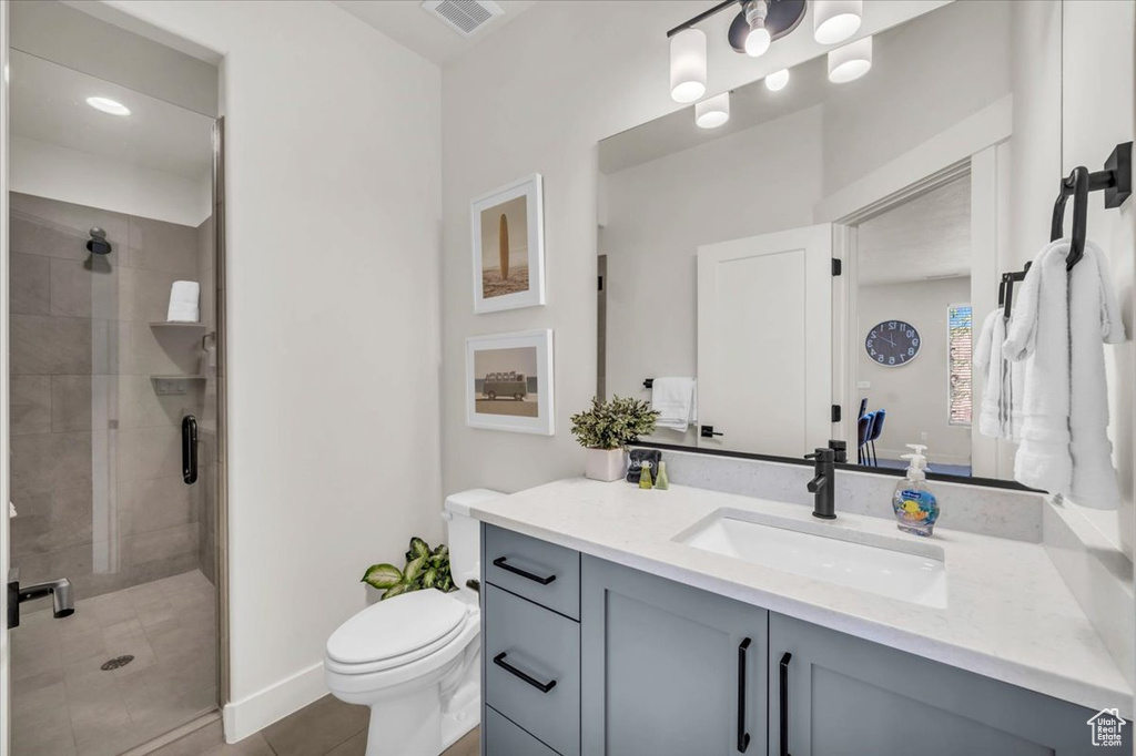 Bathroom with tile patterned floors, toilet, vanity, and an enclosed shower