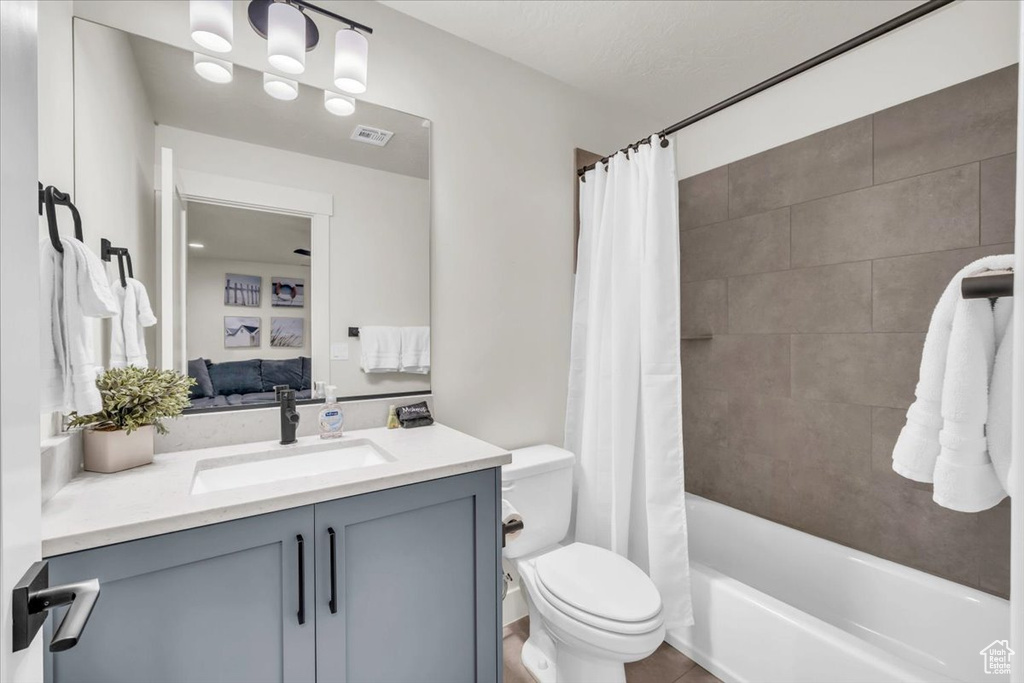 Full bathroom featuring vanity, shower / bath combo with shower curtain, and toilet