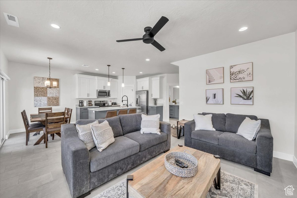 Living room featuring ceiling fan with notable chandelier and light tile patterned floors