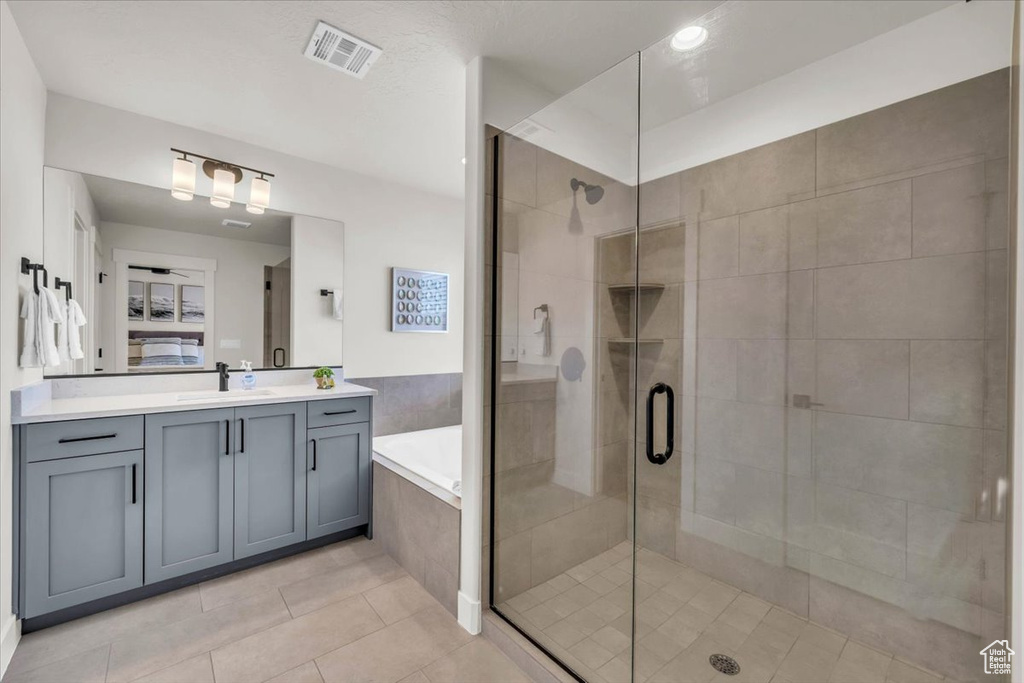 Bathroom featuring separate shower and tub, tile patterned floors, and vanity