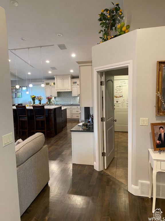 Kitchen with pendant lighting, dark hardwood / wood-style floors, a kitchen breakfast bar, and backsplash