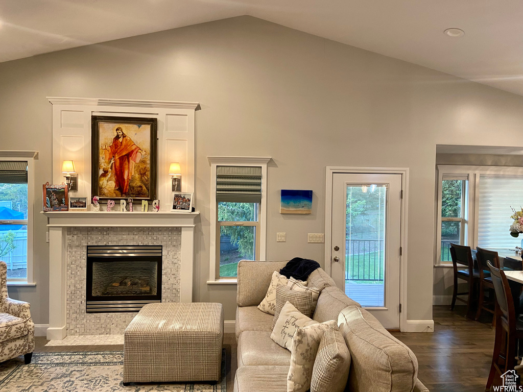 Living room featuring vaulted ceiling, a tile fireplace, and hardwood / wood-style floors