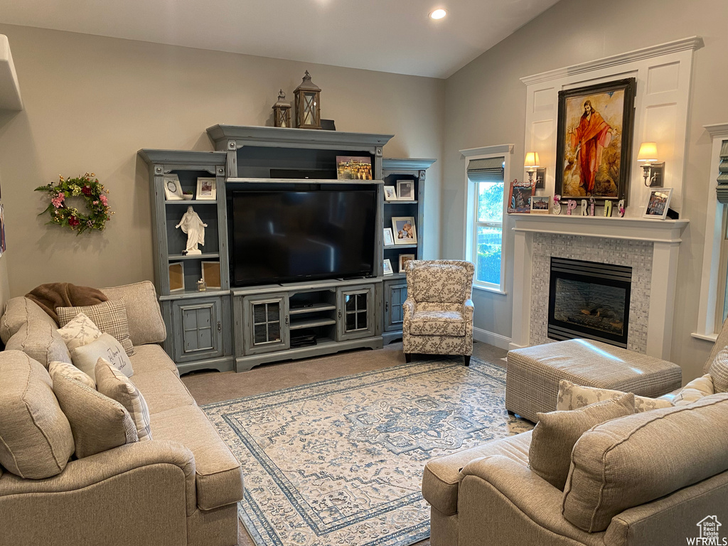 Carpeted living room with a fireplace and lofted ceiling