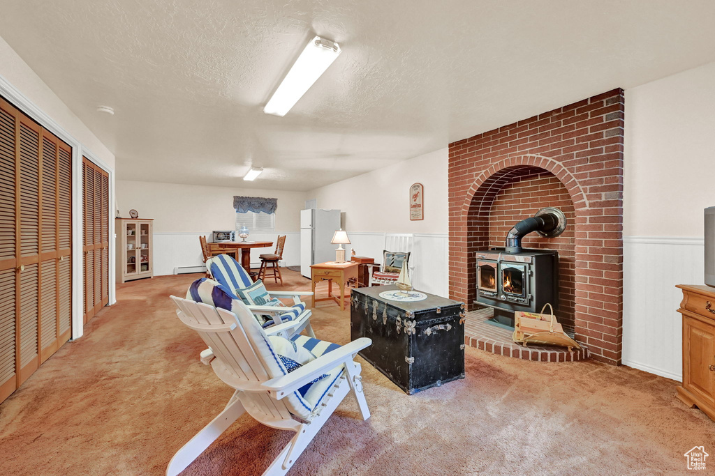 Living room with brick wall, a wood stove, a textured ceiling, and light colored carpet