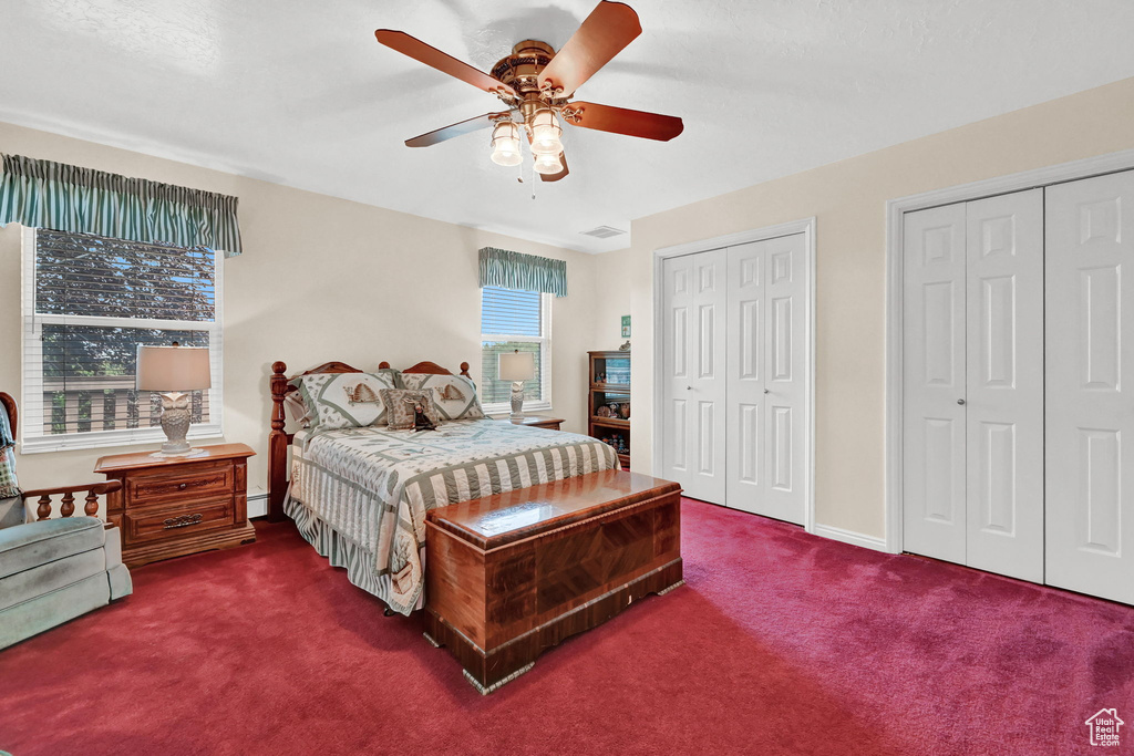 Carpeted bedroom with multiple closets, a baseboard radiator, and ceiling fan