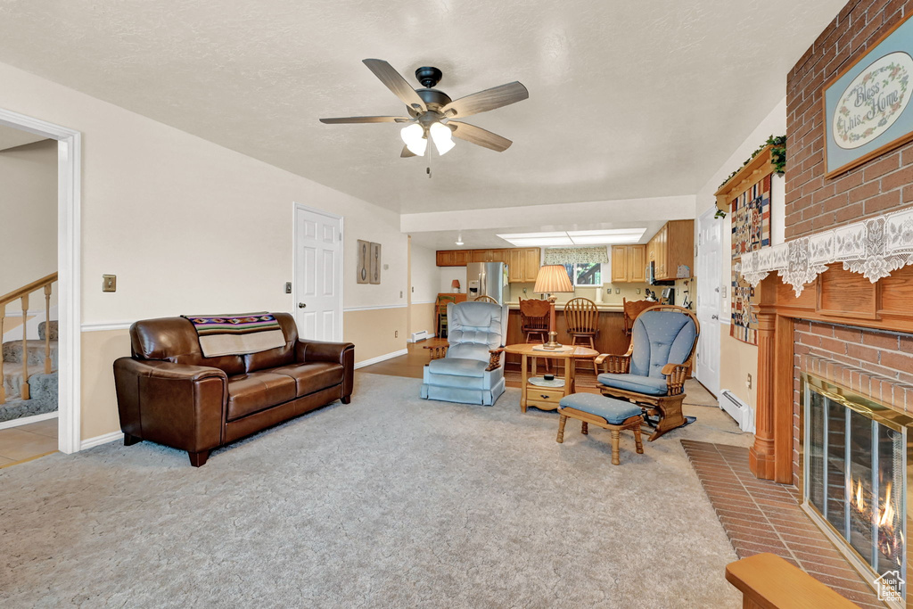 Carpeted living room with a baseboard radiator, a brick fireplace, and ceiling fan