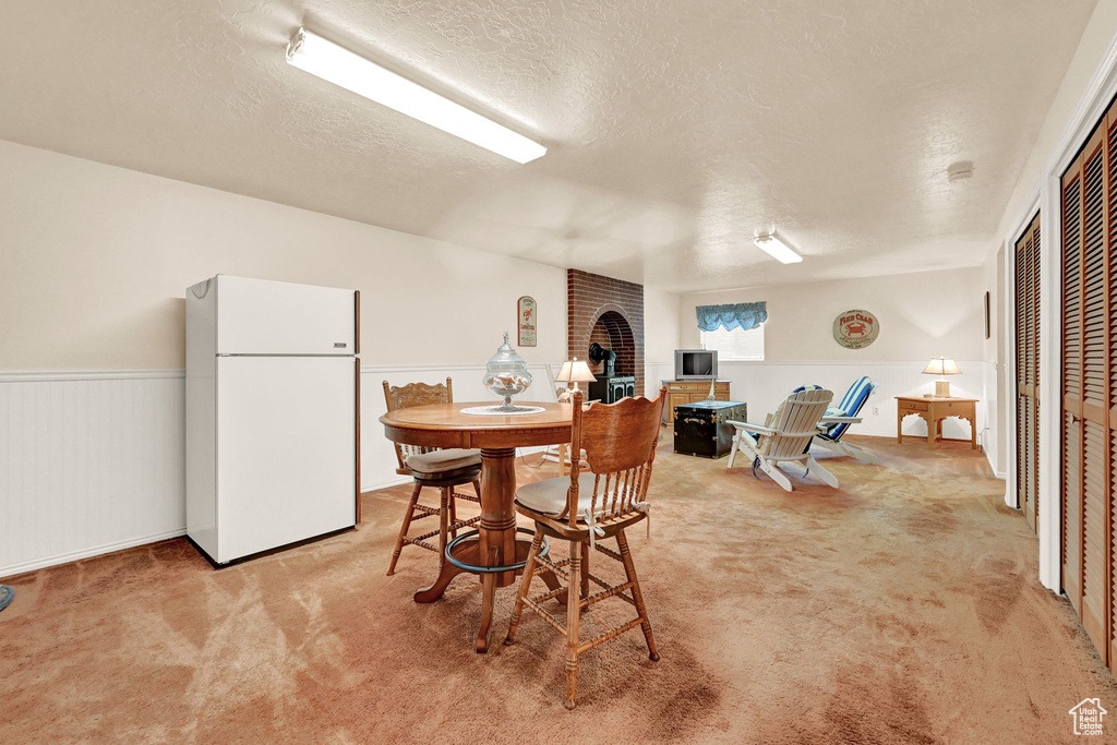 Dining room with light carpet, brick wall, and a textured ceiling