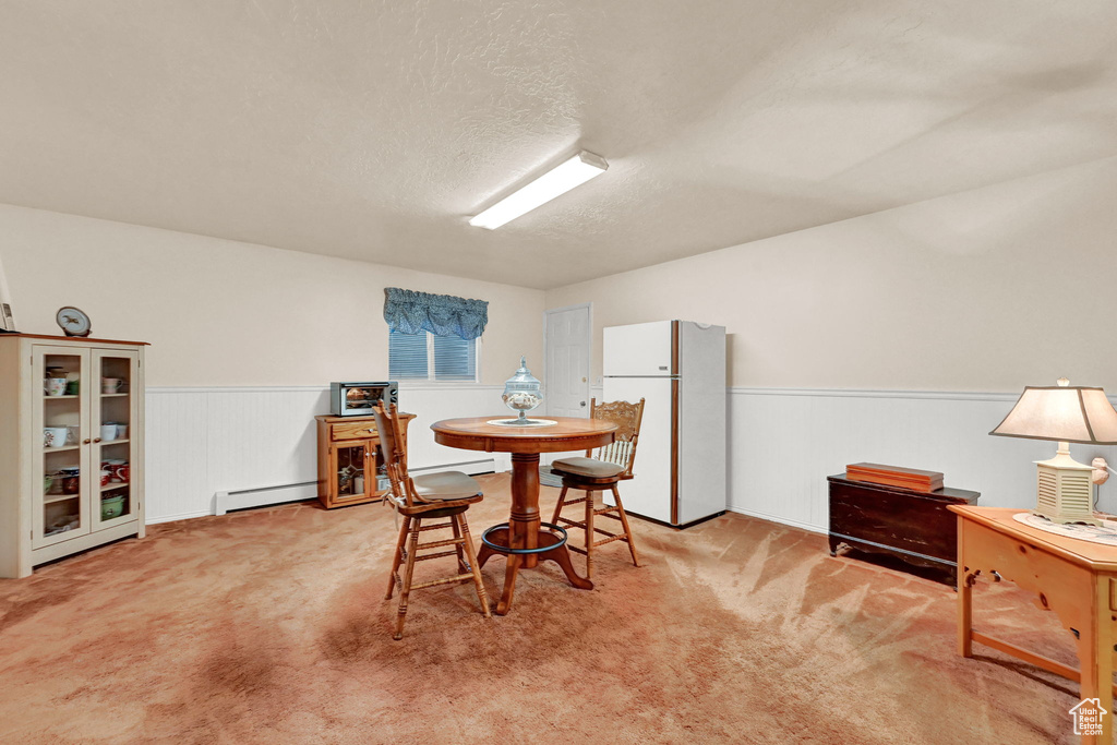 Dining room featuring baseboard heating, light colored carpet, and a textured ceiling