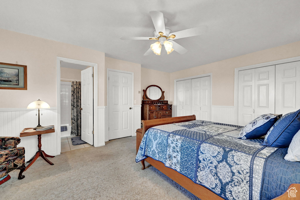 Bedroom with light carpet, ceiling fan, and two closets