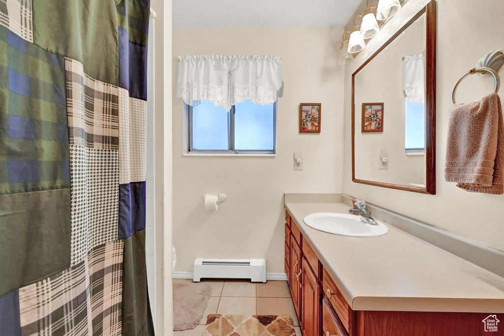 Bathroom with a baseboard heating unit, tile patterned floors, a wealth of natural light, and vanity