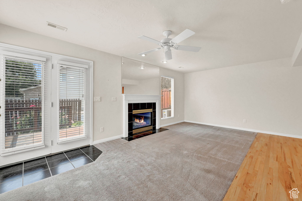 Unfurnished living room featuring hardwood / wood-style flooring, a fireplace, a healthy amount of sunlight, and ceiling fan