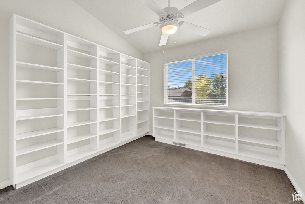 Empty room with dark colored carpet, ceiling fan, and lofted ceiling