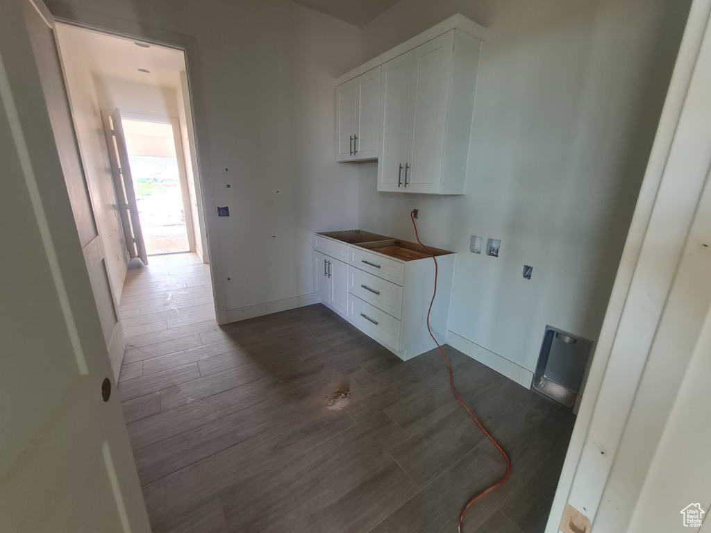 Clothes washing area with cabinets, washer hookup, and dark wood-type flooring