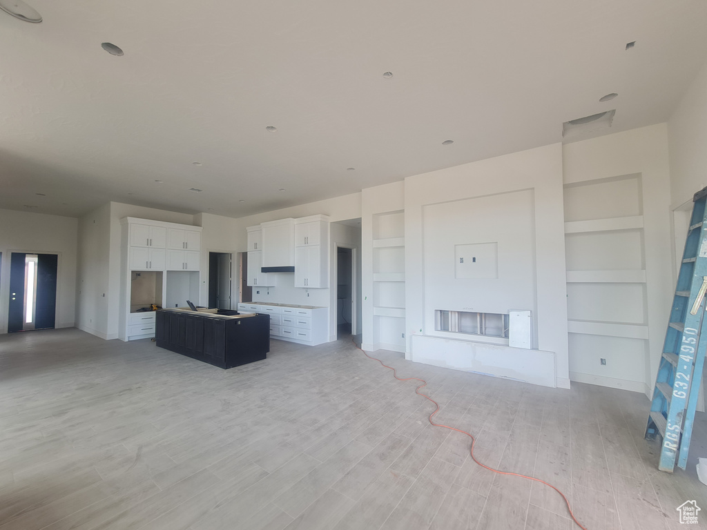 Unfurnished living room with built in features and light wood-type flooring