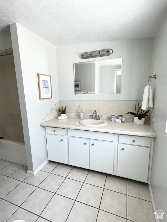 Bathroom featuring a textured ceiling, vanity, and tile patterned flooring