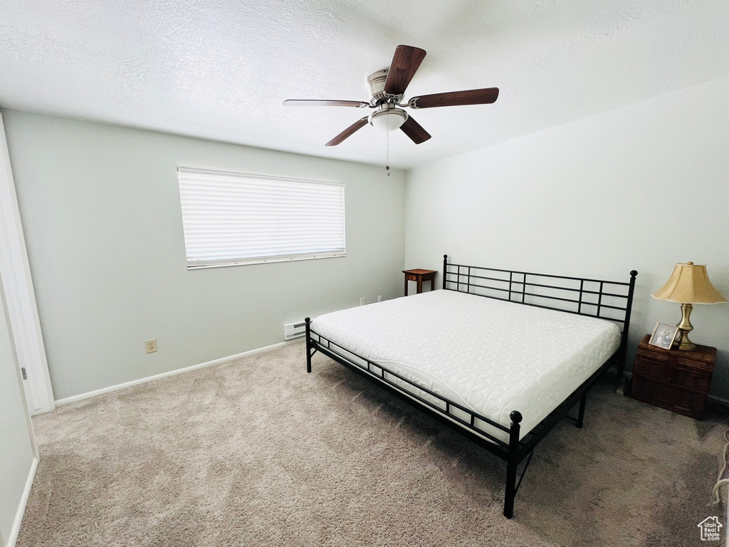 Carpeted bedroom featuring a textured ceiling and ceiling fan