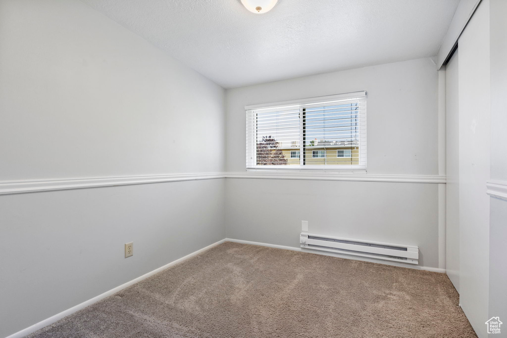 Carpeted empty room with a baseboard heating unit