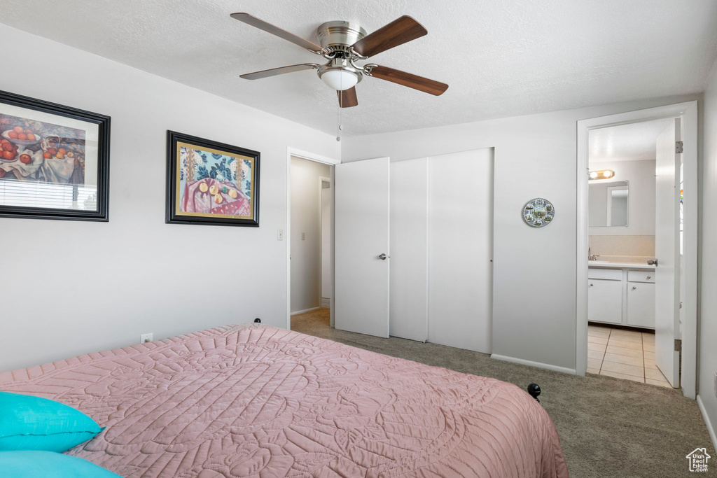 Bedroom with light tile patterned flooring, ensuite bath, and ceiling fan