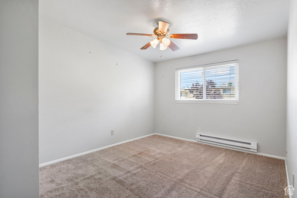 Carpeted spare room with a baseboard radiator and ceiling fan