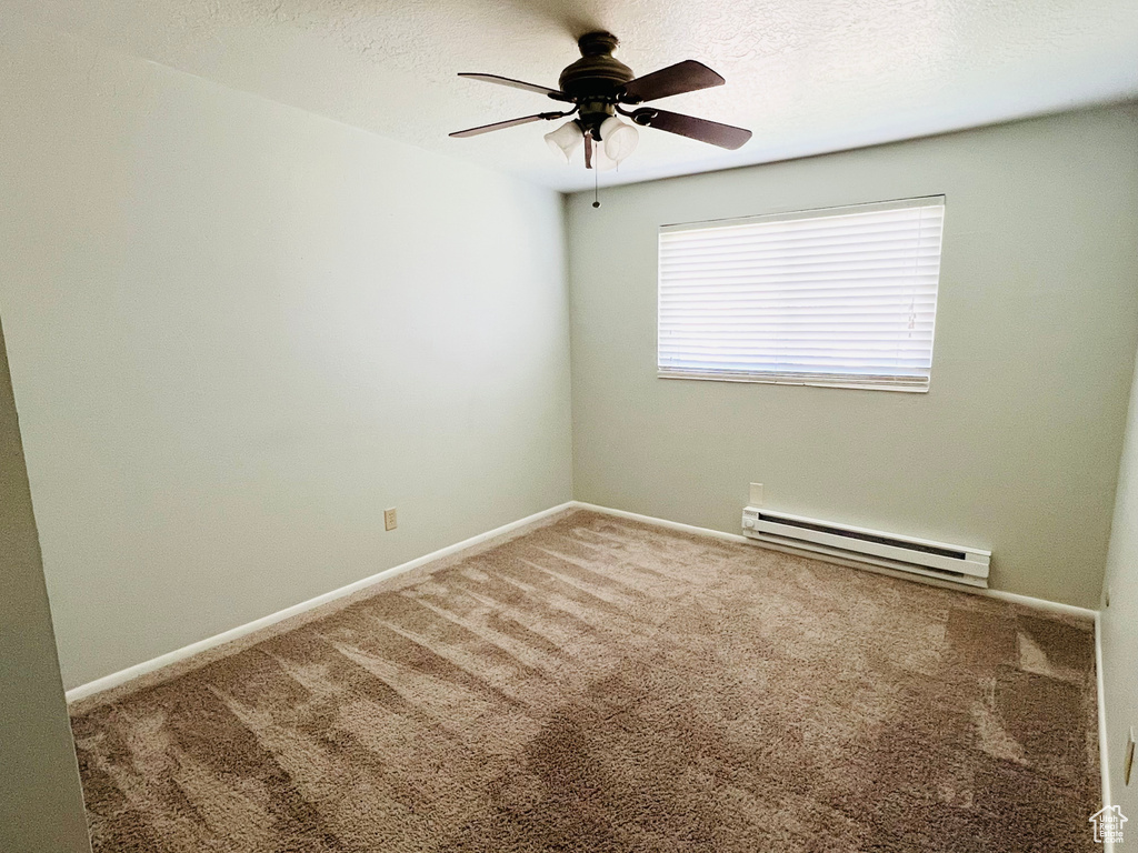 Carpeted empty room featuring a baseboard radiator and ceiling fan