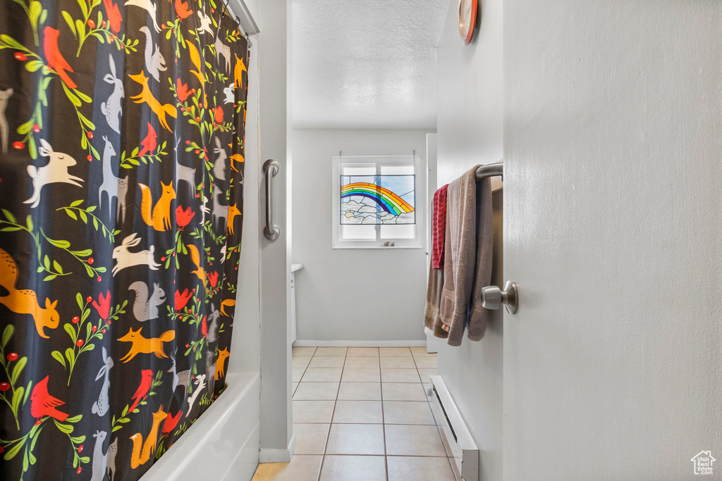 Bathroom with tile patterned flooring, a baseboard heating unit, shower / bath combo, and a textured ceiling