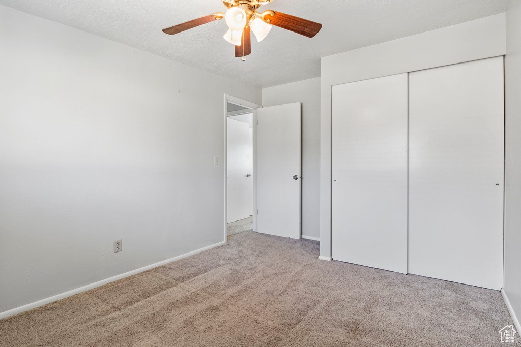 Unfurnished bedroom featuring light carpet, ceiling fan, and a closet